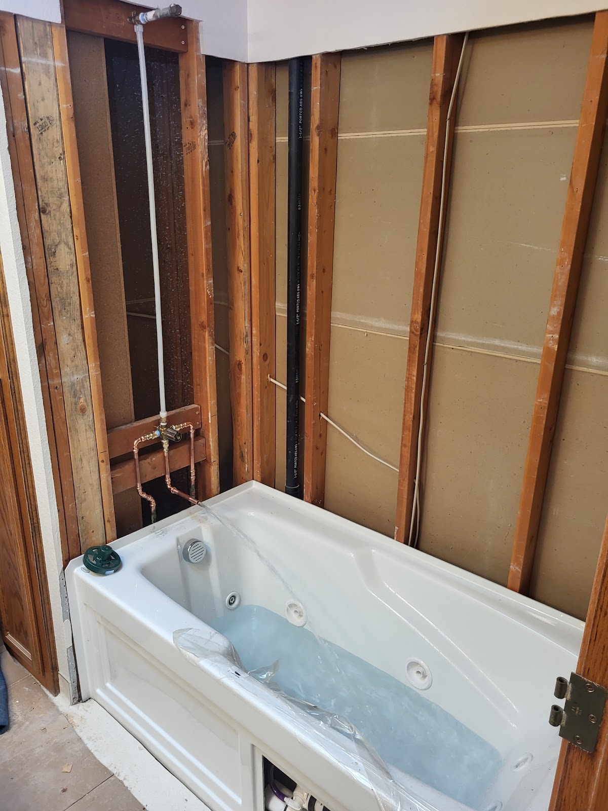 A bathtub plumbing rough-in tested and running clean before the walls are closed up